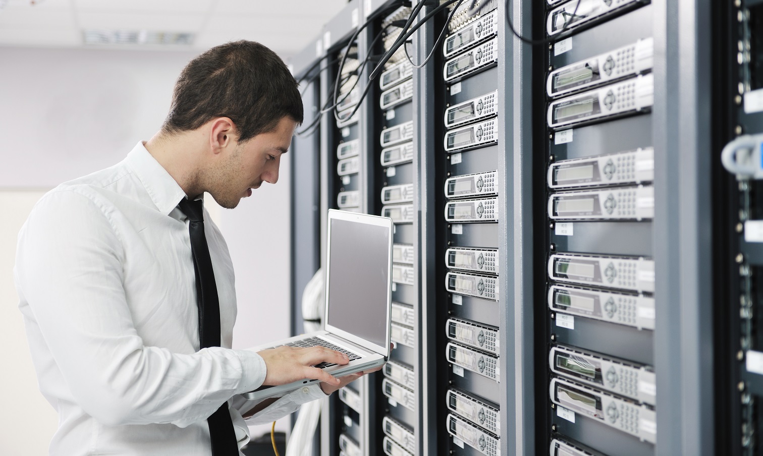 businessman with laptop in network server room